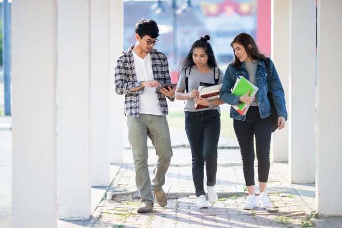 mahasiswa kemenkeu tiga orang mahasiswa berjalan menyusuri lorong kampus