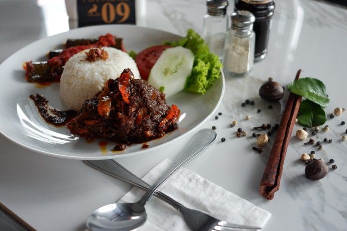 Resep Olahan Daging Sapi Rendang Olahan daging sapi rendang dihidangkan di atas piring bersama nasi